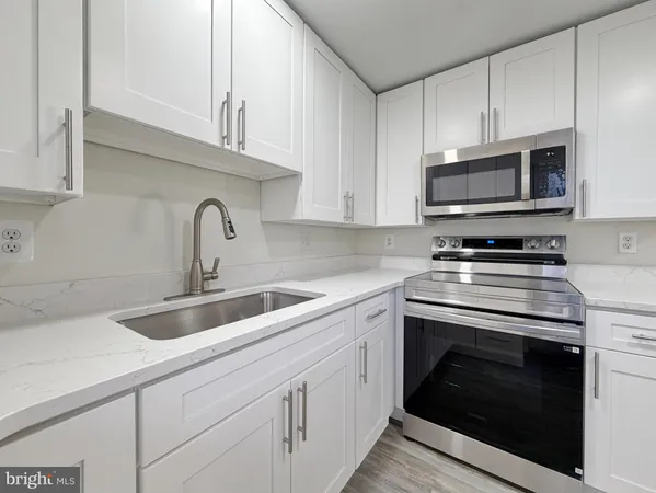 a kitchen with granite countertop a stove sink and cabinets