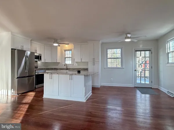 a kitchen with granite countertop a refrigerator and wooden floor
