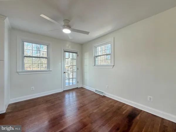 a view of an empty room with wooden floor and window