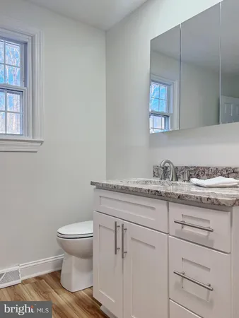 a bathroom with a granite countertop toilet sink and mirror