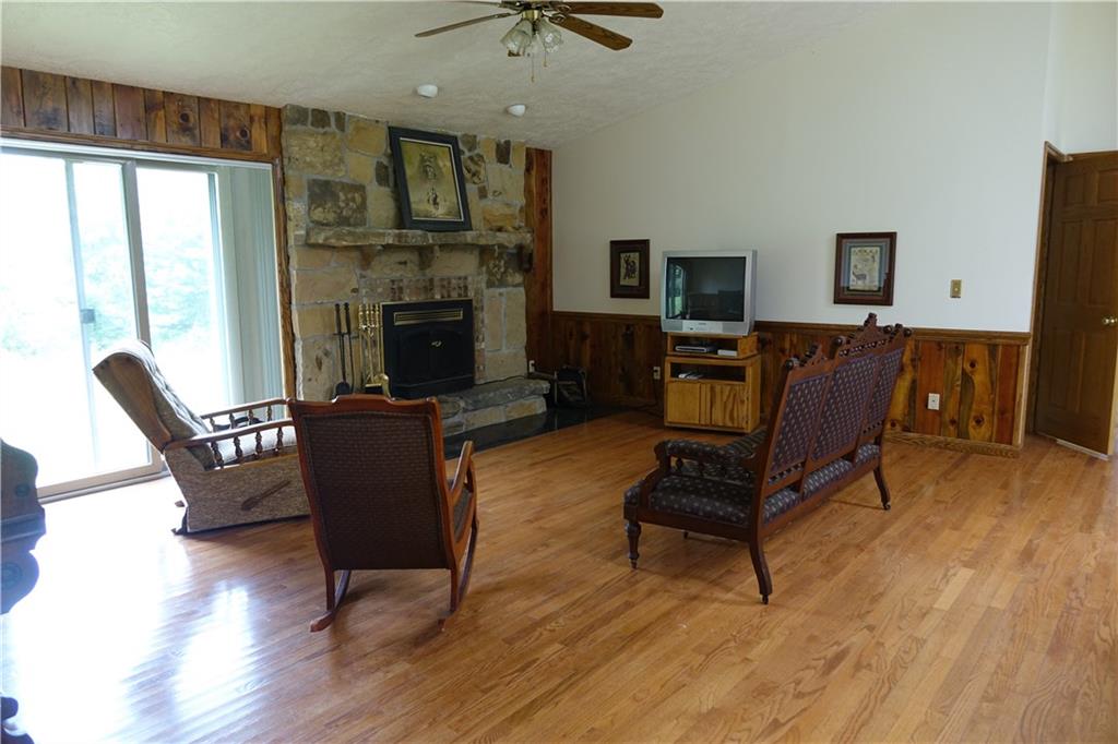 917 New Castle Road Butler, PA 16001 - Photo 2 of 25 Living room with hardwood flooring, stone fireplace, and sliding glass doors