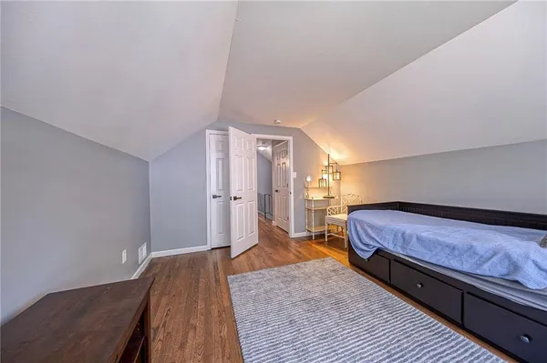 a spacious bedroom with a bed and wooden floor