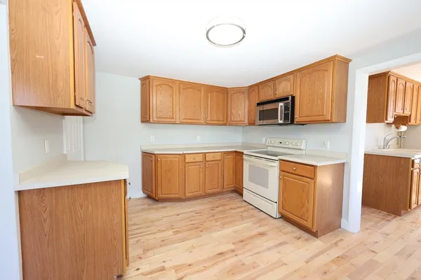 a kitchen with stainless steel appliances granite countertop a stove a sink dishwasher and a microwave oven with wooden cabinets