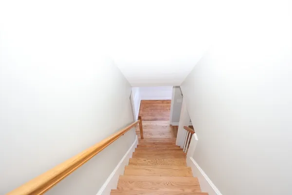 a hallway with wooden floor and a bathroom
