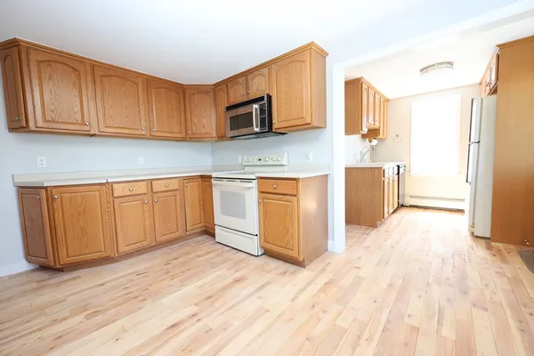 a kitchen with stainless steel appliances granite countertop a refrigerator a stove top oven a sink and dishwasher with wooden floor
