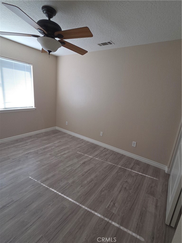10141 Rochester Road Phelan, CA 92371 - Photo 16 of 22 an empty room with wooden floor fan and windows