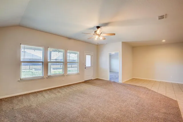 an empty room with chandelier fan and windows