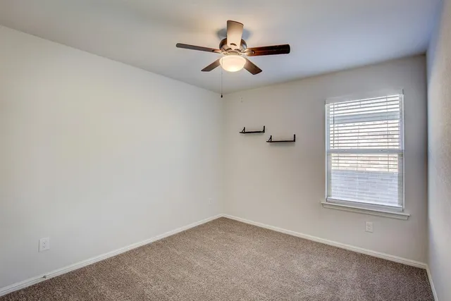 an empty room with a window and a fan