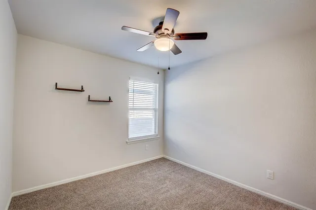 an empty room with a window and a ceiling fan