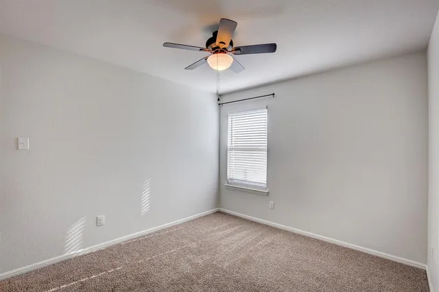 an empty room with a window and a ceiling fan