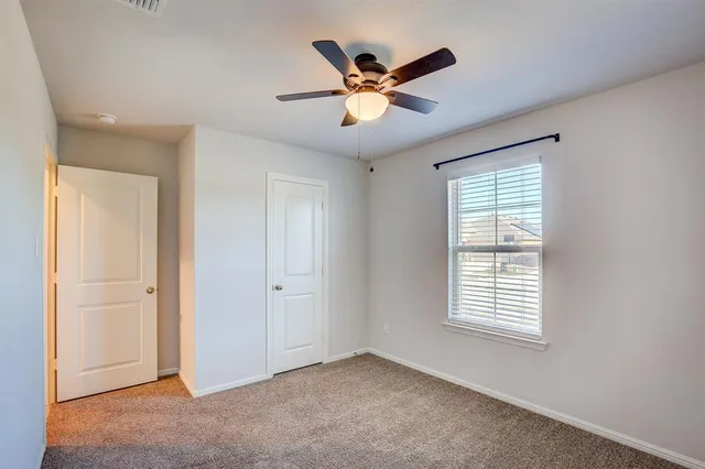 a view of an empty room with a ceiling fan and window