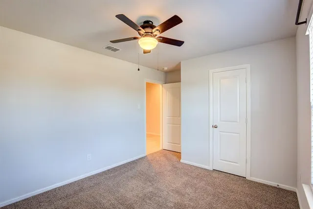 an empty room with ceiling fan and window