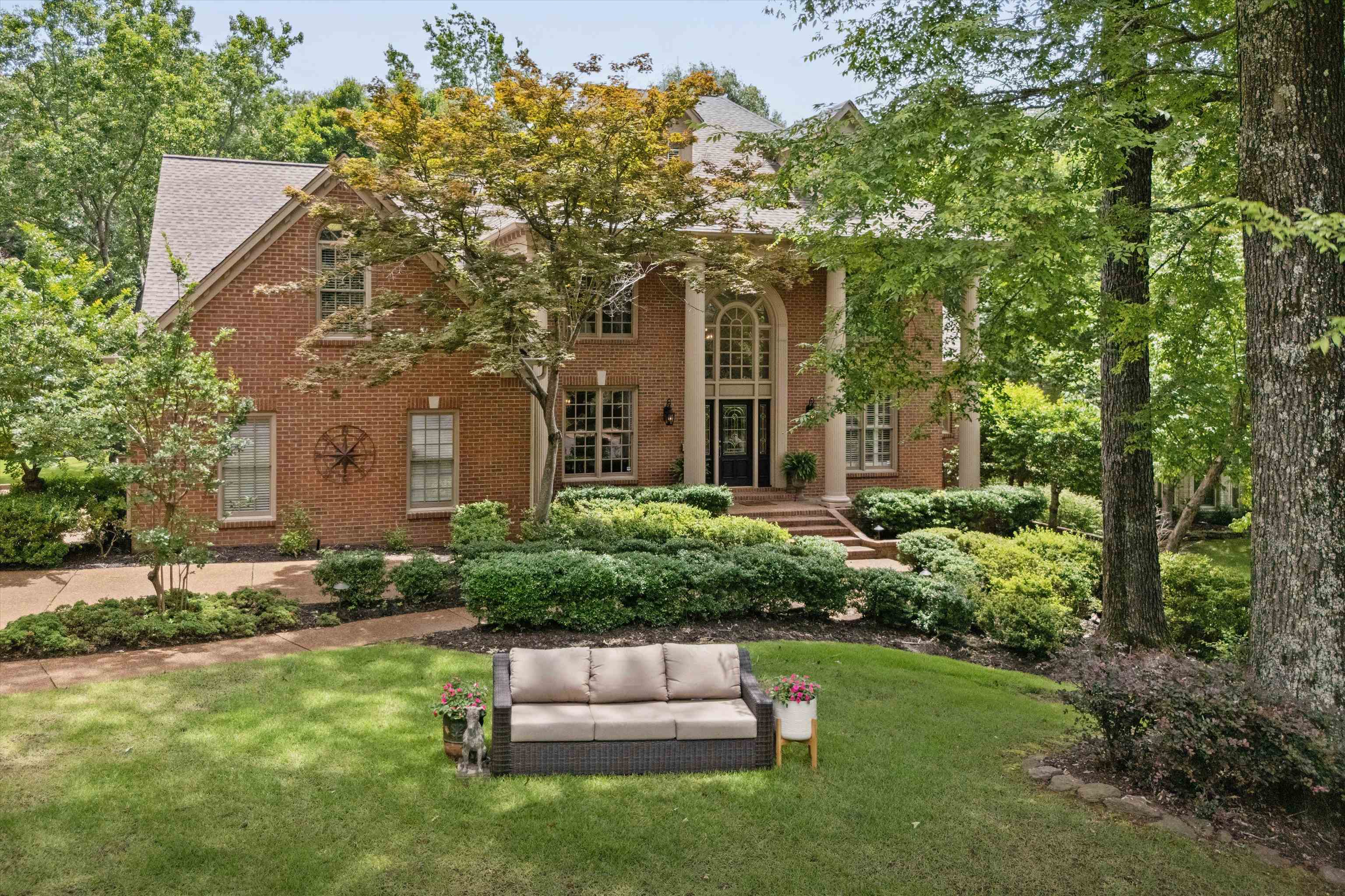 View of front facade featuring brick siding, a front lawn, and outdoor lounge area
