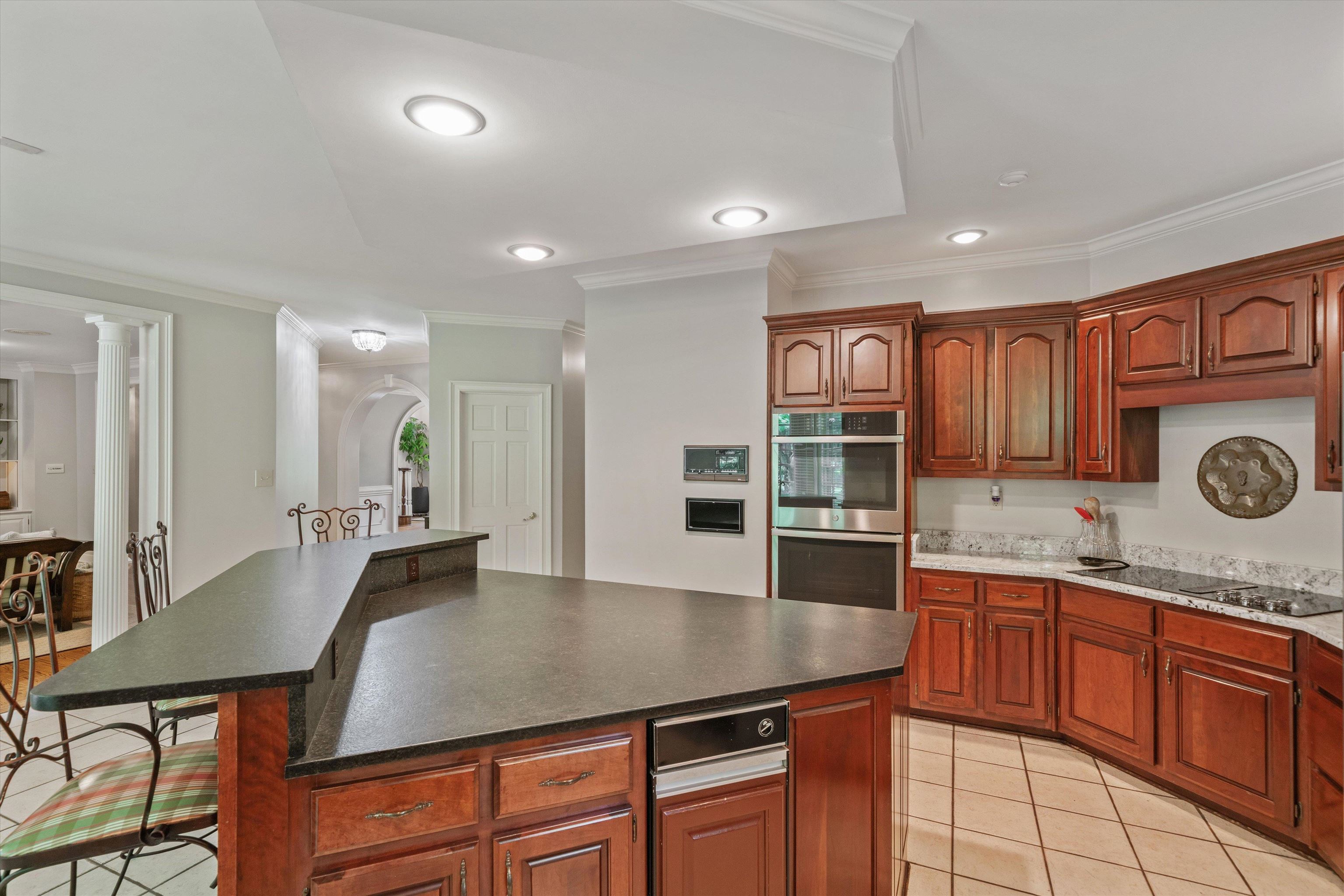 8897 Forest Ridge Cove Memphis, TN 38018 - Photo 11 of 35 Kitchen with stainless steel double oven, crown molding, black electric cooktop, a center island, and dark countertops
