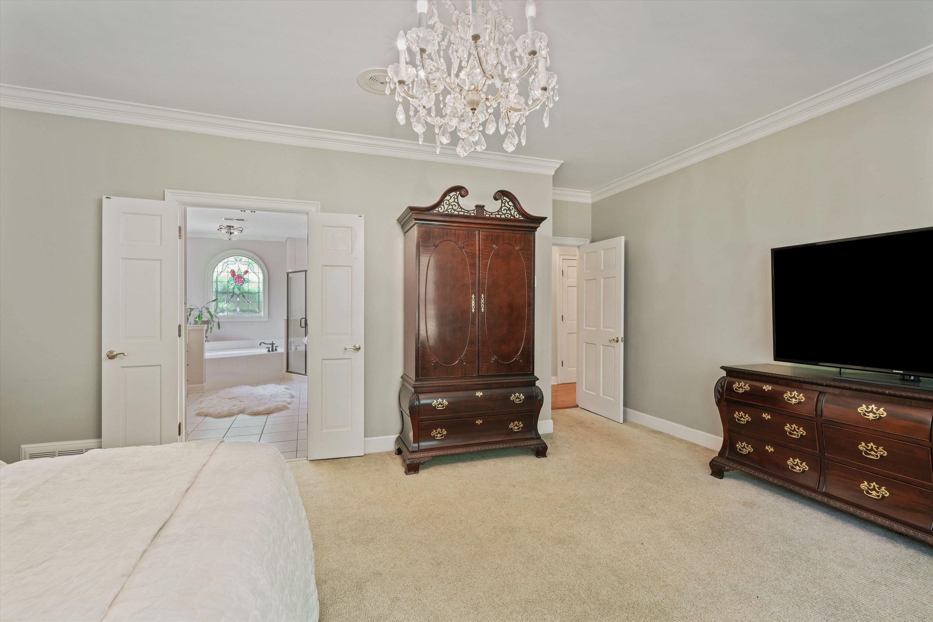 8897 Forest Ridge Cove Memphis, TN 38018 - Photo 16 of 35 Bedroom featuring light carpet, ornamental molding, and a chandelier
