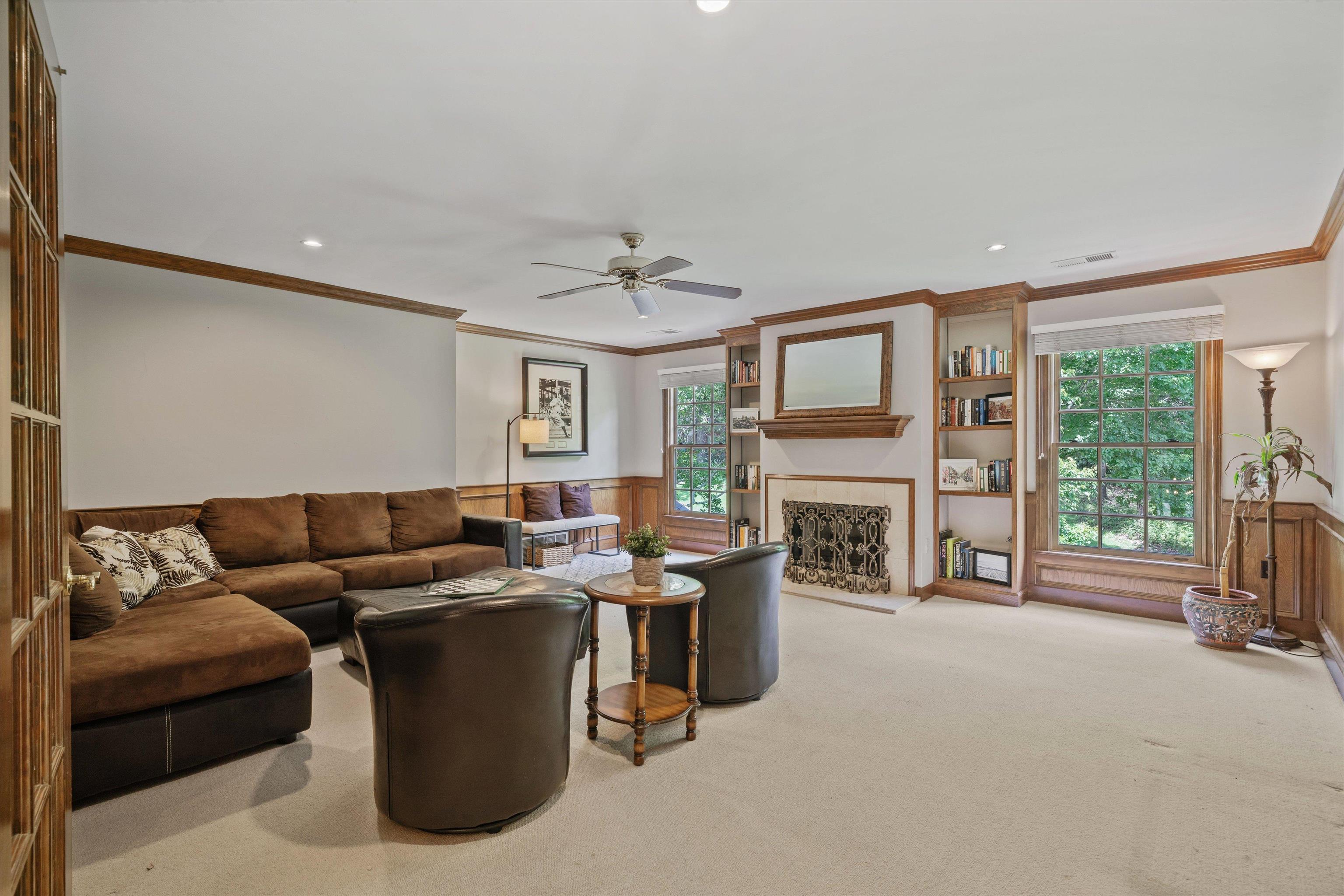 8897 Forest Ridge Cove Memphis, TN 38018 - Photo 26 of 35 Carpeted living room with ornamental molding, wainscoting, ceiling fan, a fireplace with raised hearth, and recessed lighting