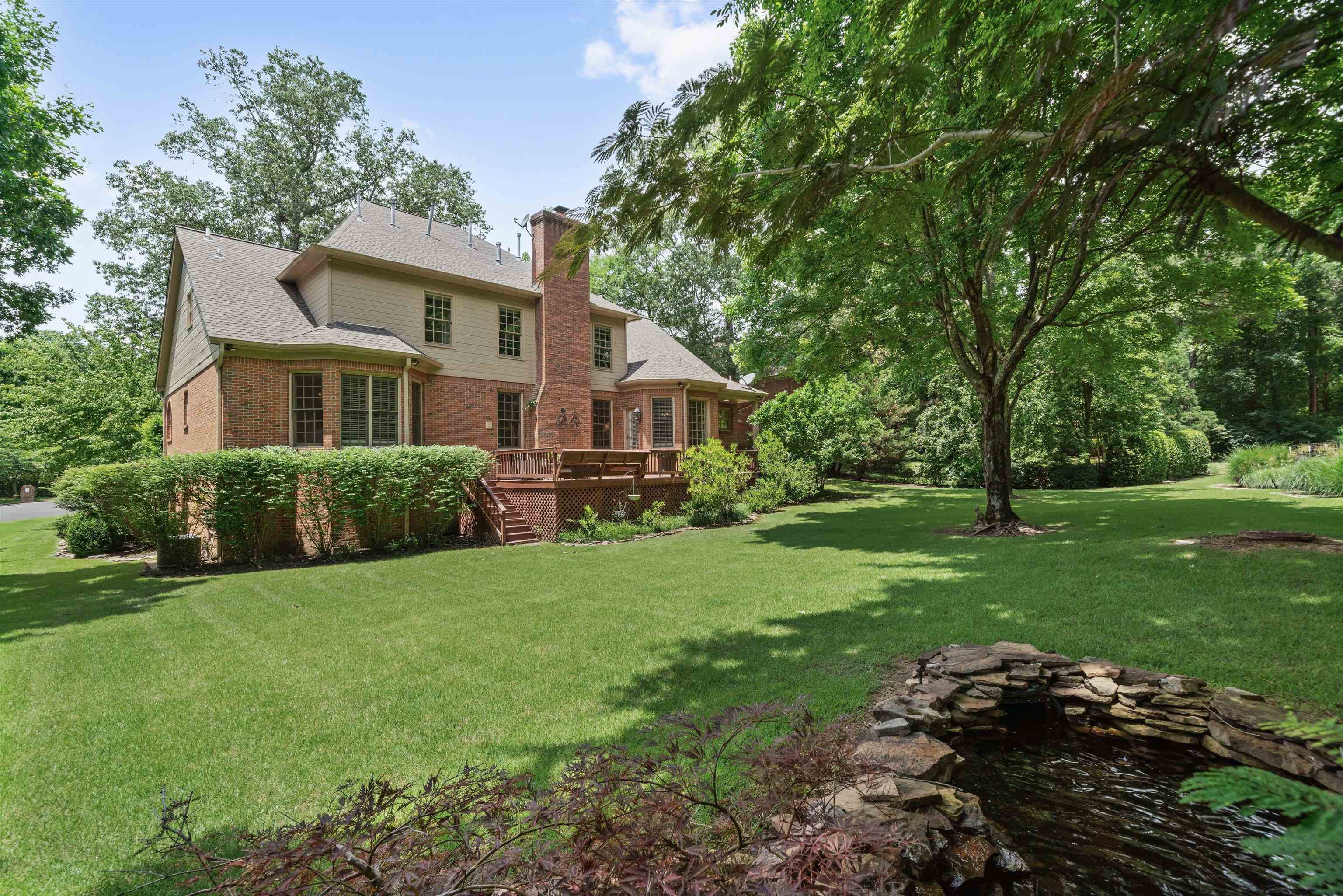 8897 Forest Ridge Cove Memphis, TN 38018 - Photo 31 of 35 Back of house with brick siding, a chimney, a deck, and a yard