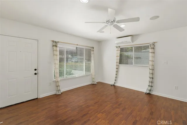 an empty room with wooden floor fan and windows