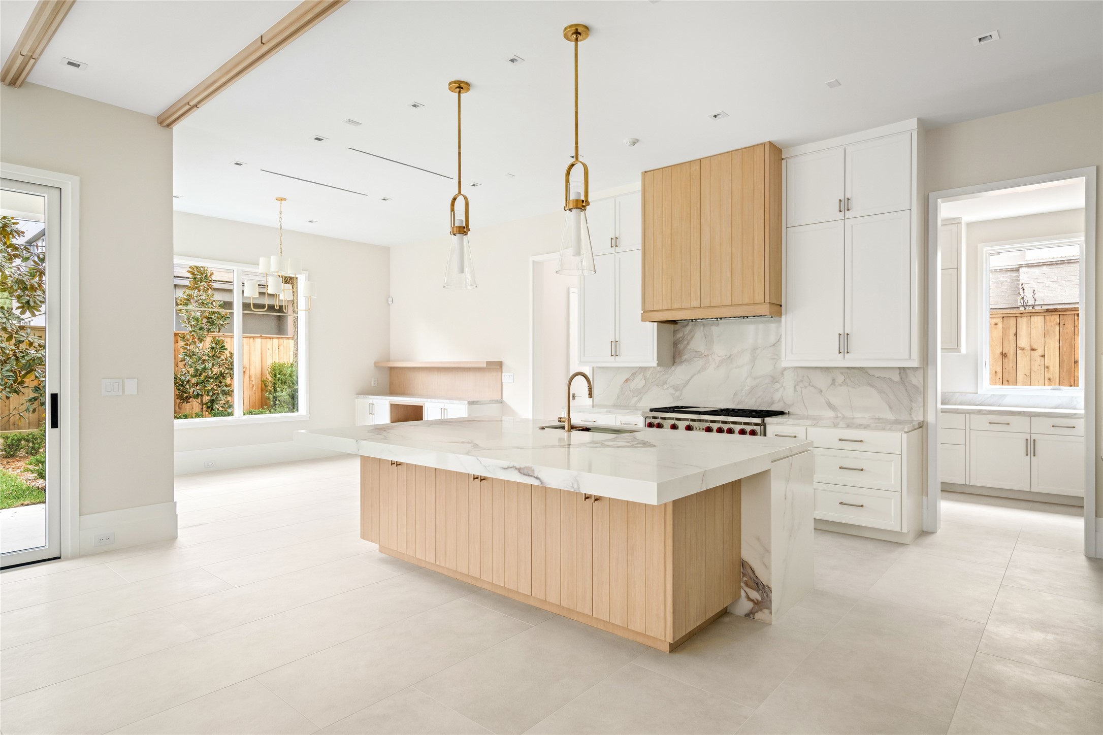 4006 Overbrook Lane Houston, TX 77027 - Photo 13 of 50 Warm wood detailing and sculptural lighting elevate the kitchen, while waterfall stone surfaces and abundant storage—within the island and throughout—add both beauty and function.