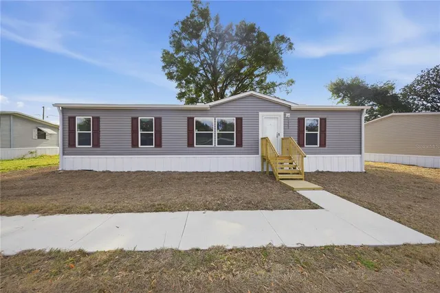 a view of a house with a yard and large tree