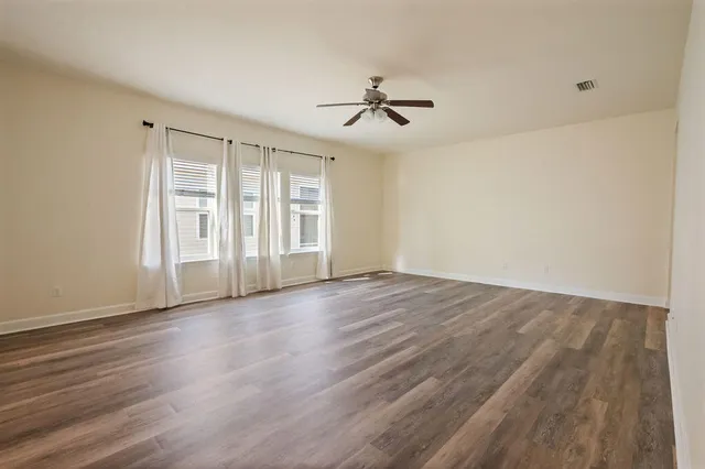 a view of empty room with wooden floor and ceiling fan