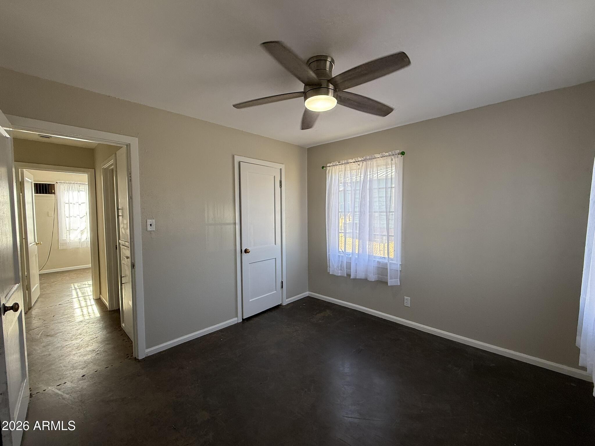 91 Neptune Avenue Bisbee, AZ 85603 - Photo 10 of 12 an empty room with wooden floor fan and windows