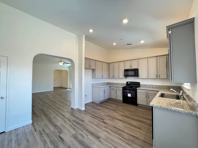 a kitchen with stainless steel appliances granite countertop a refrigerator a stove top oven a sink dishwasher and wooden floor