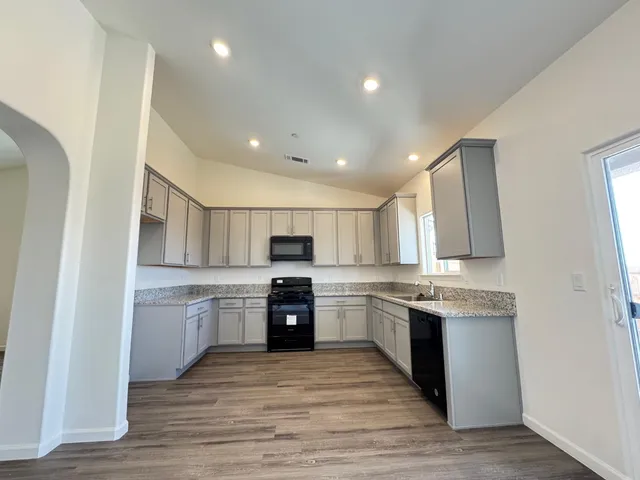 a kitchen with stainless steel appliances granite countertop a stove top oven a sink dishwasher and a refrigerator