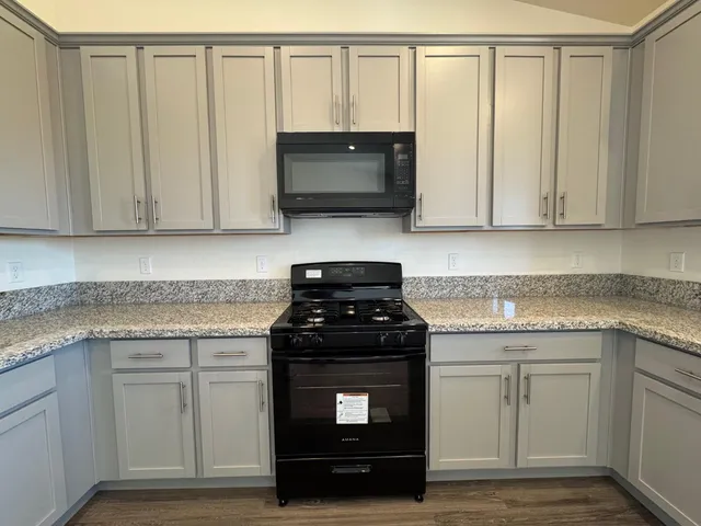 a kitchen with granite countertop white cabinets and a stove top oven