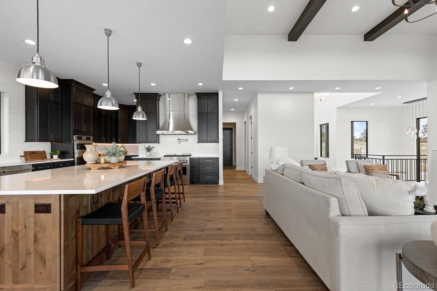11115 Evening Hunt Road Franktown, CO 80116 - Photo 13 of 46 a large white kitchen with a large island oven a sink dishwasher and white cabinets with wooden floor