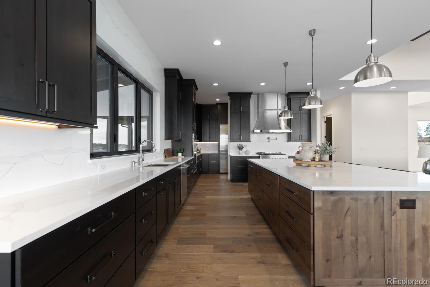 11115 Evening Hunt Road Franktown, CO 80116 - Photo 17 of 46 a large kitchen with a large counter top a sink stainless steel appliances and cabinets