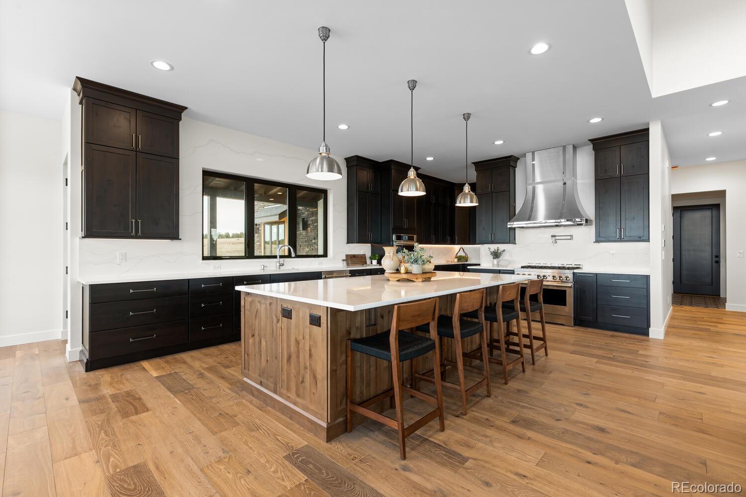 11115 Evening Hunt Road Franktown, CO 80116 - Photo 20 of 46 a large kitchen with kitchen island a sink stainless steel appliances and cabinets