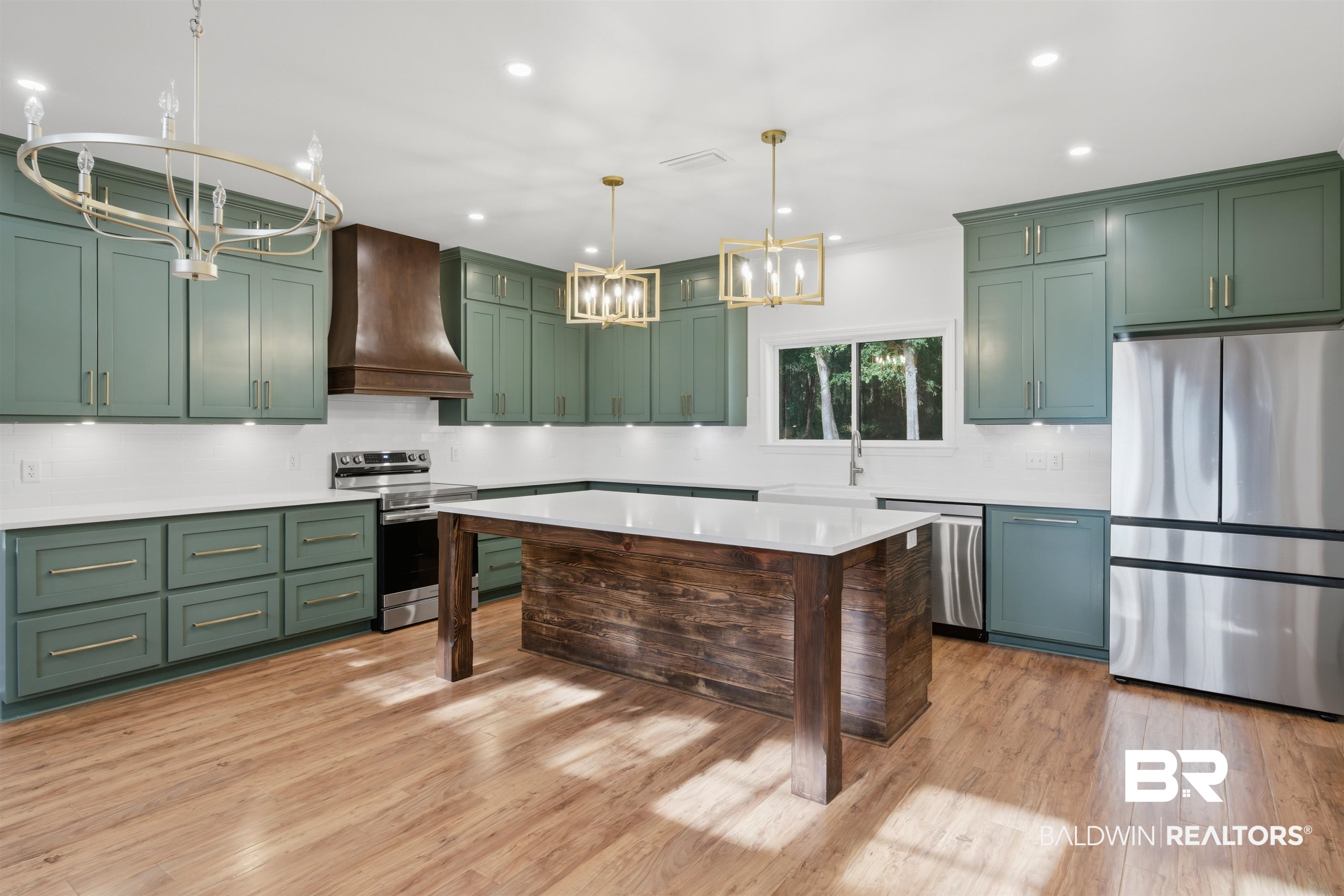 14128 Jackson Lane Foley, AL 36535 - Photo 9 of 36 Spacious kitchen featuring sage green cabinetry, a central island with a wood-finish base, stainless steel appliances, white countertops, and wood-finish flooring