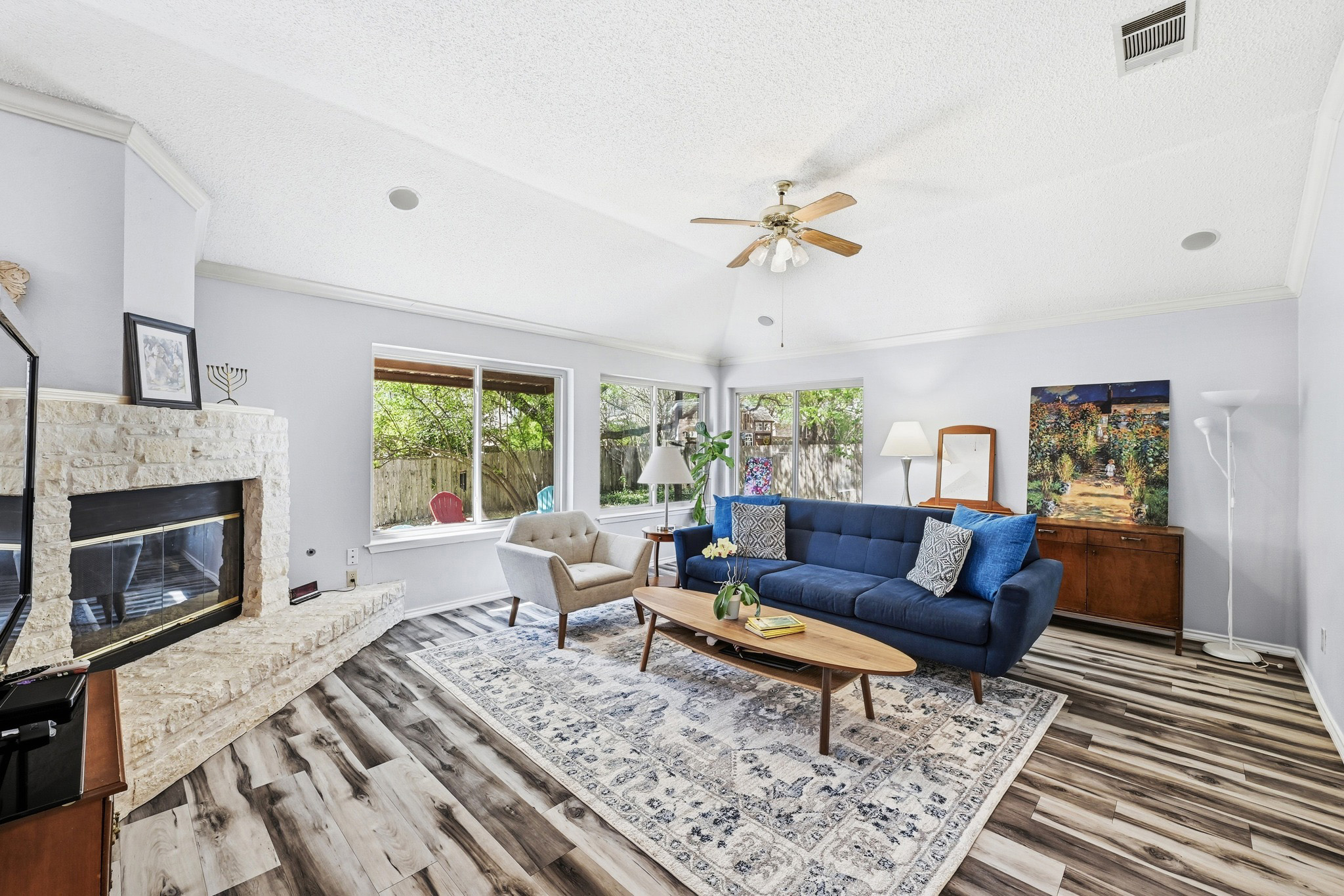 10803 Pinkney Lane Austin, TX 78739 - Photo 12 of 38 Living area featuring wood finished floors, a glass covered fireplace, ceiling fan, and ornamental molding