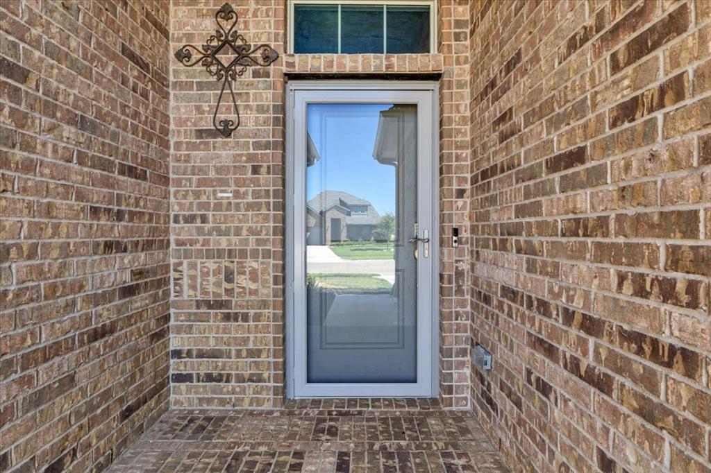 1402 Pleasanton Road Cleburne, TX 76033 - Photo 5 of 36 Brick exterior with a storm door, transom window, and brick-patterned porch flooring