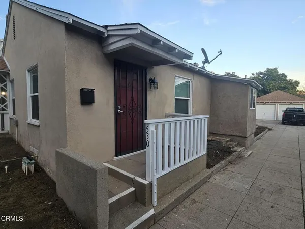 a view of a house with a small yard and wooden floor and fence