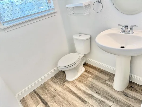 a view of a hallway with wooden floor and a bathroom