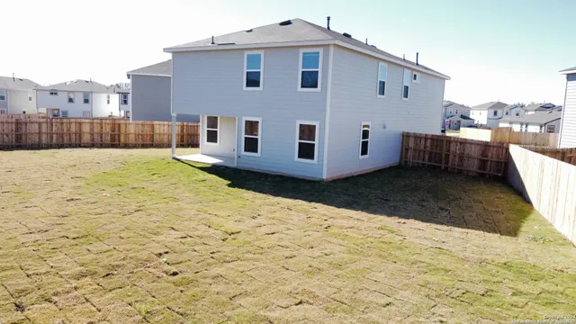 a view of a house with backyard and wooden fence