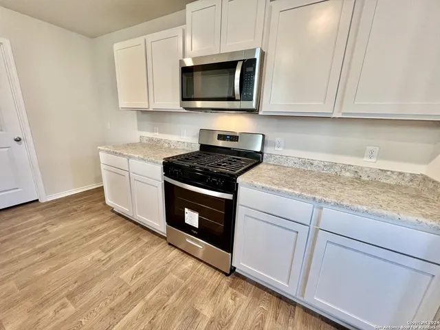a kitchen with granite countertop cabinets stainless steel appliances and a wooden floor