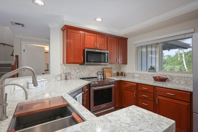 a kitchen with granite countertop wooden cabinets a sink and a stove