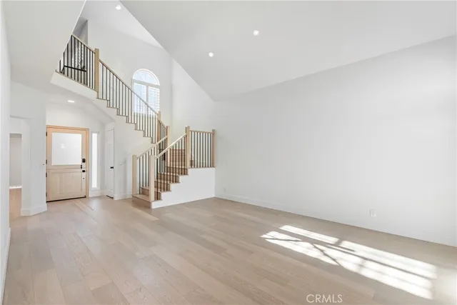 a view of an empty room with wooden floor and stairs