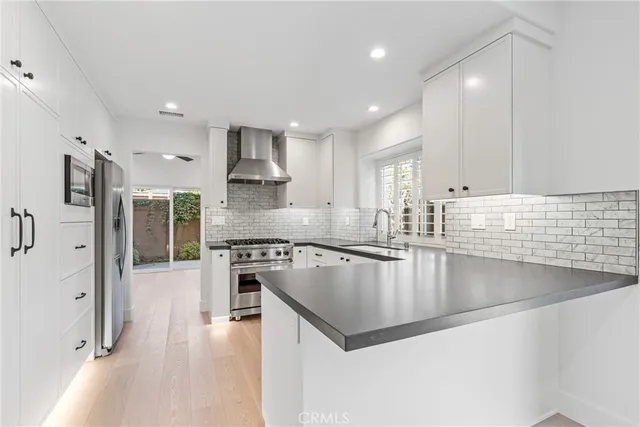 a large kitchen with stainless steel appliances granite countertop a lot of counter space and wooden floors