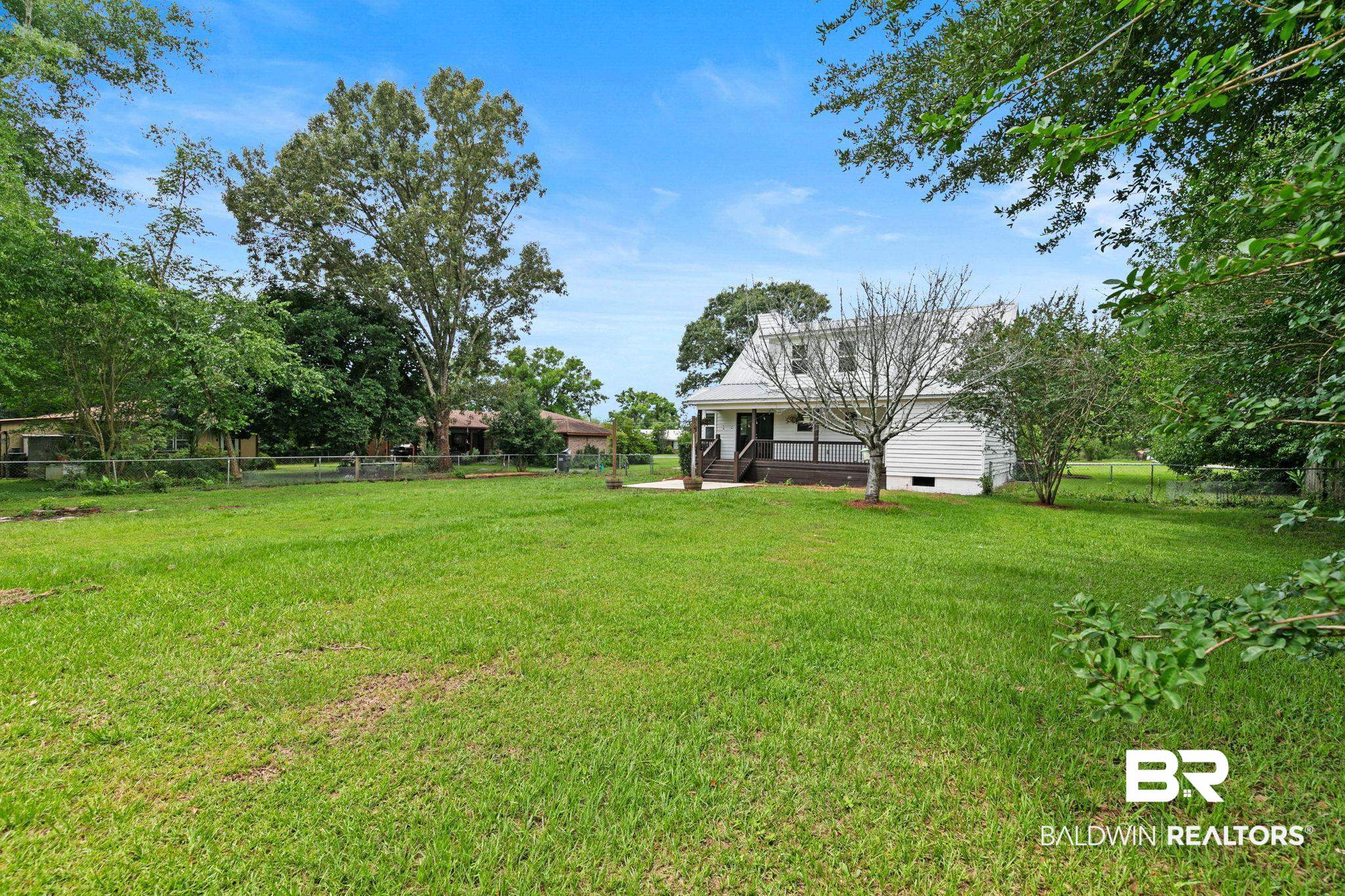 22810 High Ridge Road Fairhope, AL 36532 - Photo 57 of 78 Expansive green lawn with mature perimeter trees and a white two-story residence featuring a porch and exterior stairs