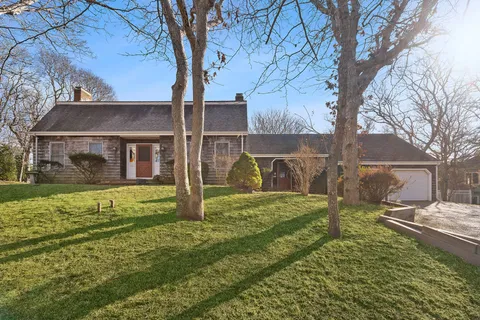 a view of a yard in front of a house with large tree
