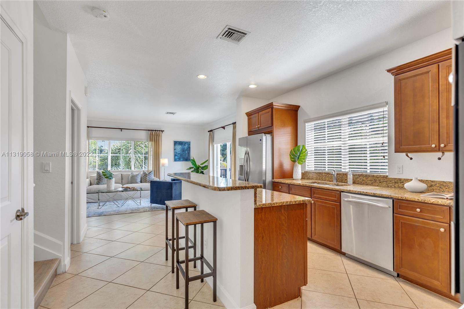 674 Northwest Library Commons Way, Unit 674 Boca Raton, FL 33432 - Photo 6 of 20 a large kitchen with kitchen island a large window cabinets and stainless steel appliances
