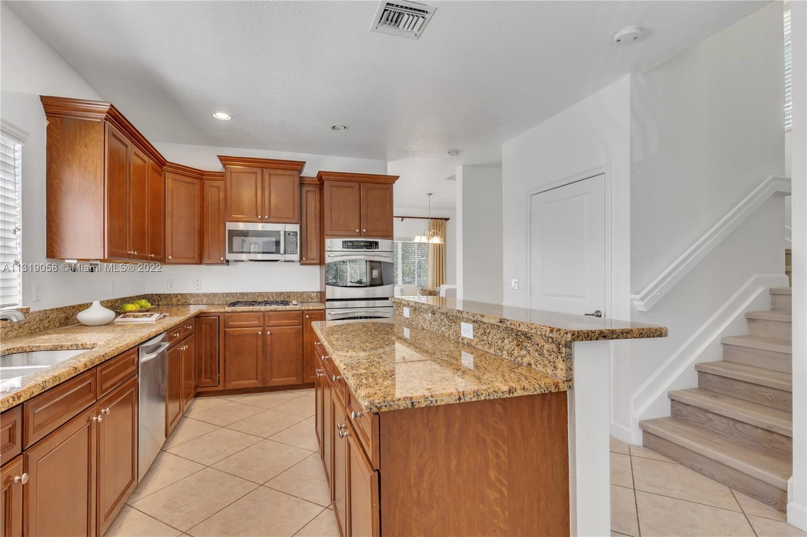 674 Northwest Library Commons Way, Unit 674 Boca Raton, FL 33432 - Photo 8 of 20 a kitchen with stainless steel appliances granite countertop a sink stove and refrigerator