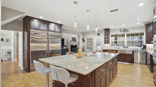 a kitchen with granite countertop kitchen island stainless steel appliances a refrigerator a stove a sink a dining table and chairs