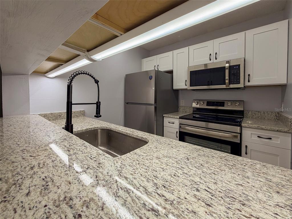 3921 Southwest 34th Street, Unit 301 Gainesville, FL 32608 - Photo 11 of 31 a kitchen with stainless steel appliances kitchen island granite countertop a refrigerator and a sink
