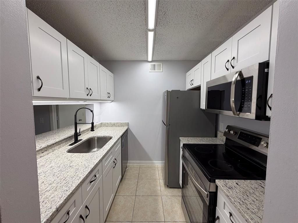 3921 Southwest 34th Street, Unit 301 Gainesville, FL 32608 - Photo 3 of 31 a kitchen with granite countertop a sink and a stove top oven