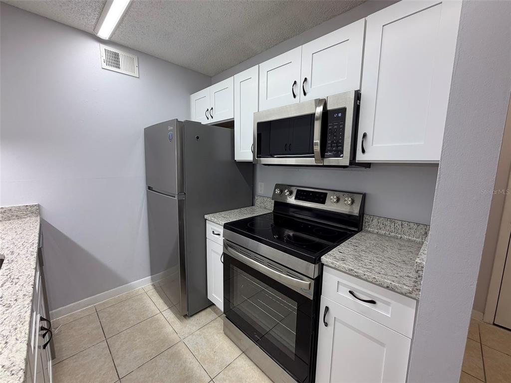 3921 Southwest 34th Street, Unit 301 Gainesville, FL 32608 - Photo 4 of 31 a kitchen with granite countertop cabinets and steel stainless steel appliances